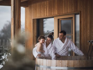 Kessler’s Mountain Lodge: awards Family in bathrobes by wooden hot tub on snowy terrace