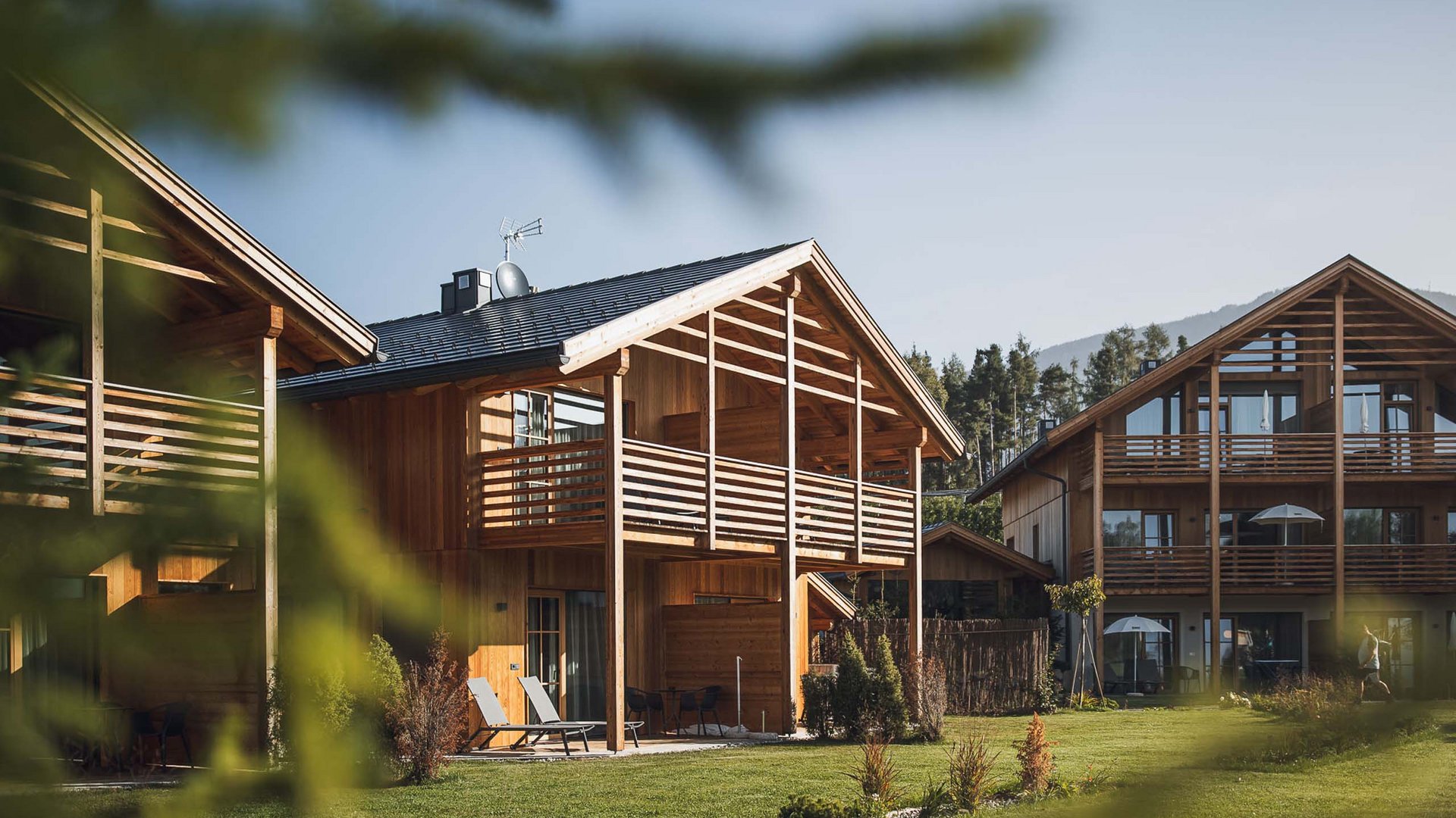 Chalet with a sauna and so much more: Kessler’s Wooden chalets with balconies and lounge chairs on green lawn in sunny weather