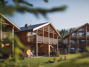 Vacanze in fattoria? Kessler’s Mountain Lodge! Chalet in legno con balconi e sdraio su prato verde sotto il sole