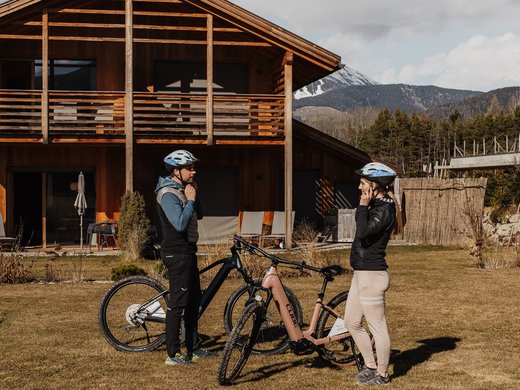 Holiday with a dog in South Tyrol: Kessler’s! Two cyclists with helmets standing by bikes in front of a wooden mountain house