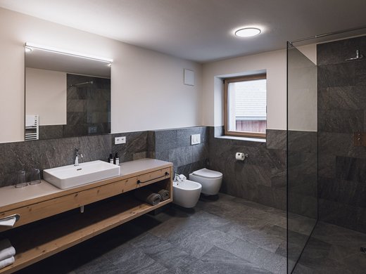 FAQ Modern bathroom with vanity sink, toilet, bidet and spacious glass shower