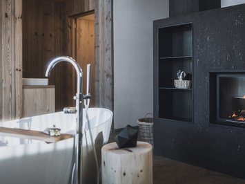 Chalet with a sauna and so much more: Kessler’s Modern fireplace next to freestanding bathtub in wood interior