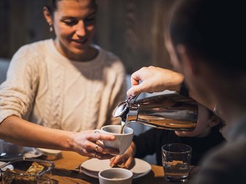 Bontà locali e di stagione al Klessler’s Donna tiene una tazza mentre un uomo versa caffè da una thermos