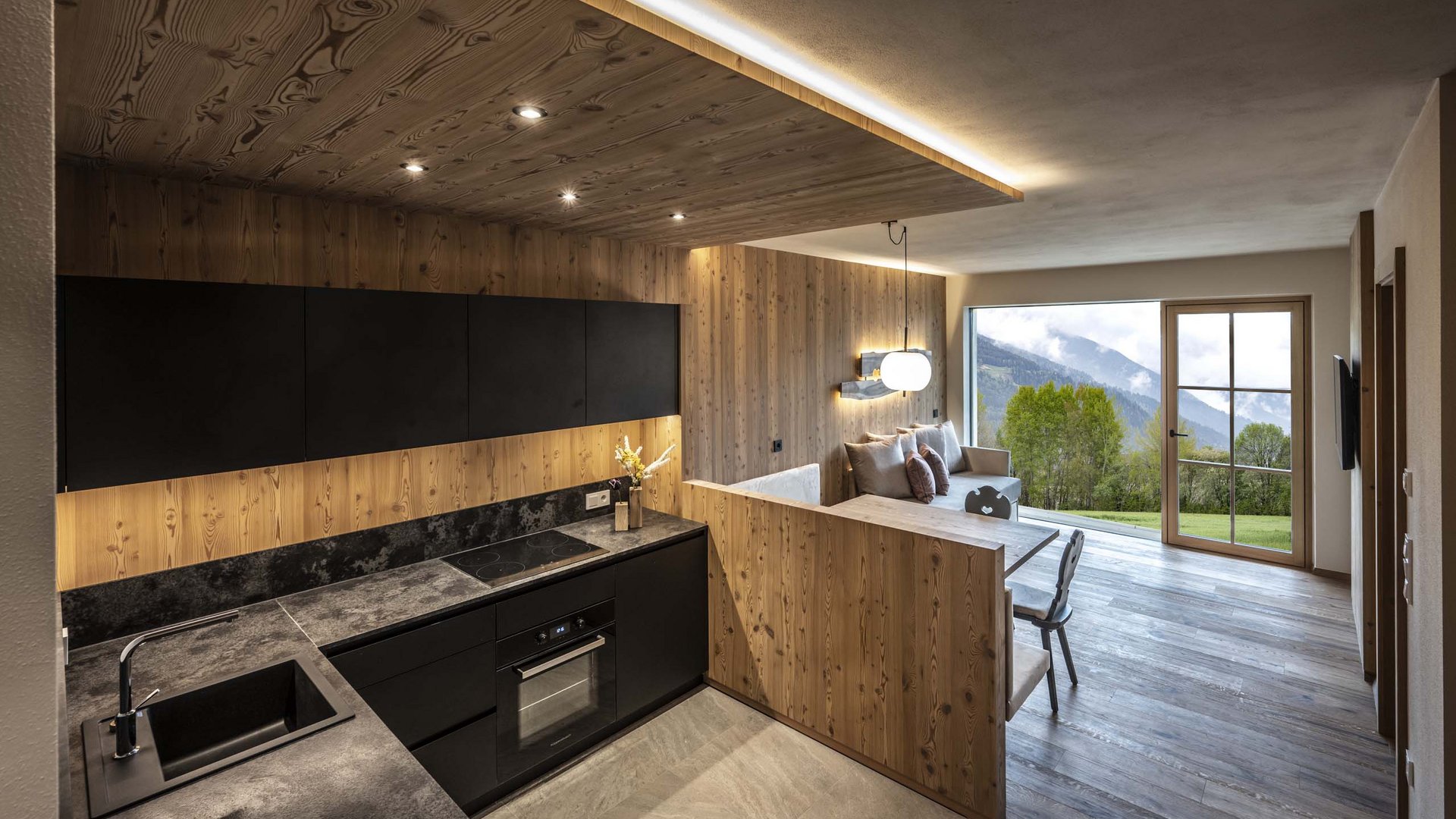 Vacanze in fattoria? Kessler’s Mountain Lodge! Cucina moderna con rivestimenti in legno e vista sulle montagne verdi