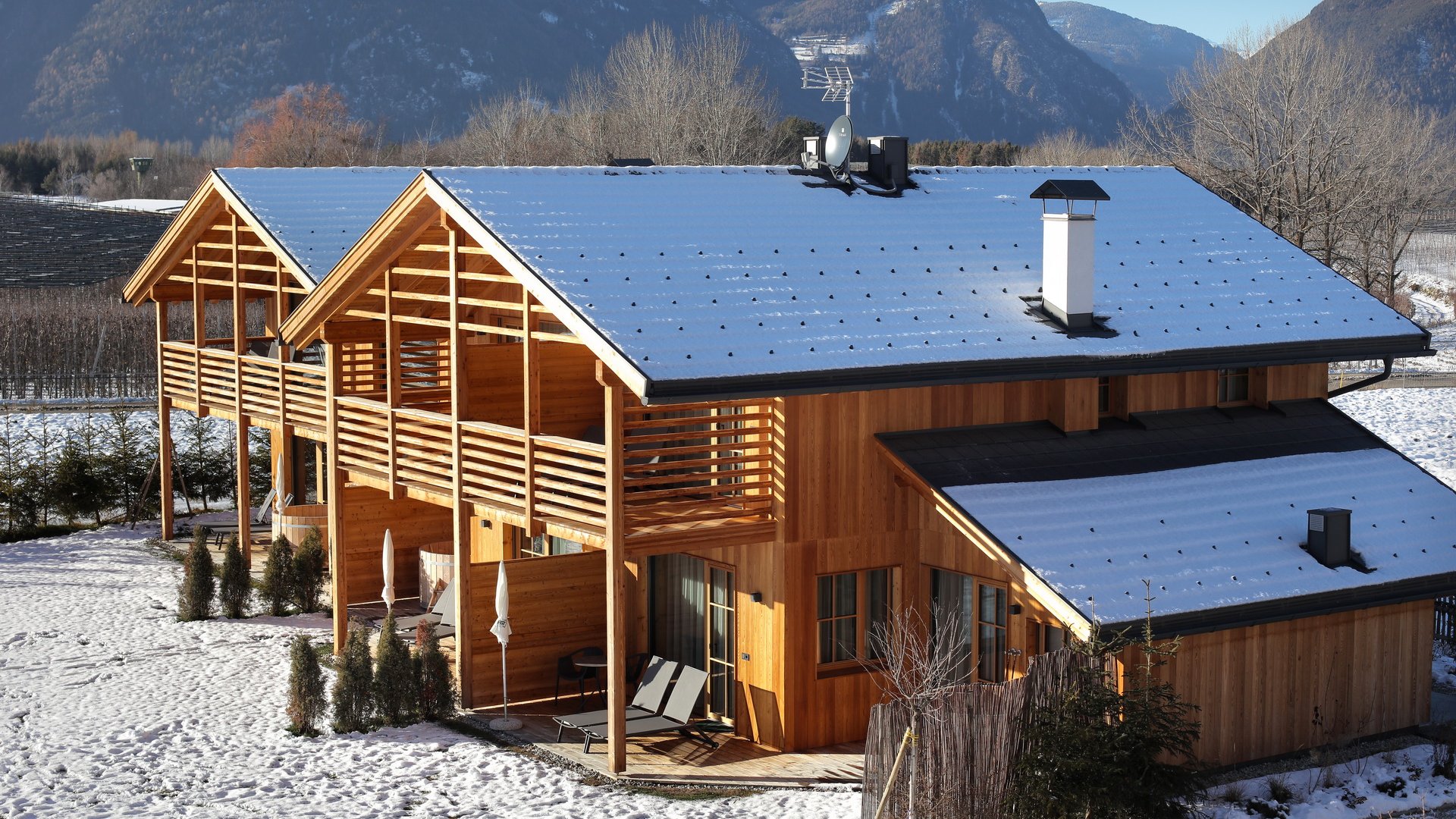 Ferienwohnung in Natz mit dem gewissen Etwas Zweistöckiges Holzhaus mit schneebedecktem Dach in einer winterlichen Berglandschaft