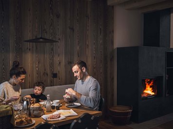Bontà locali e di stagione al Klessler’s Famiglia che fa colazione insieme a un tavolo di legno vicino al camino