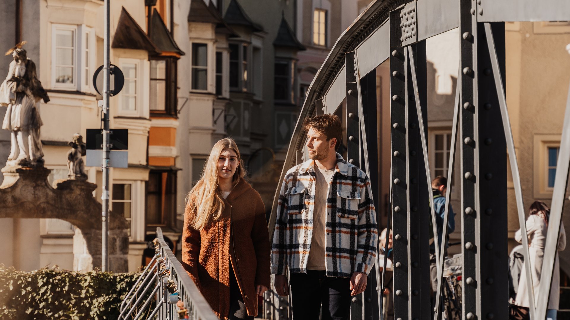Urlaub nahe Brixen voller Überraschungen Junges Paar geht bei sonnigem Wetter über eine Fußgängerbrücke in der Stadt