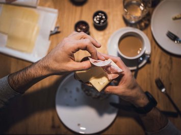 Bontà locali e di stagione al Klessler’s Persona che mette prosciutto e formaggio su pane a colazione