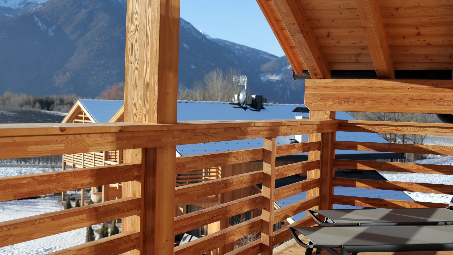 Ferienwohnung in Natz mit dem gewissen Etwas Balkon aus Holz mit Blick auf verschneite Berge und Sonnenliegen