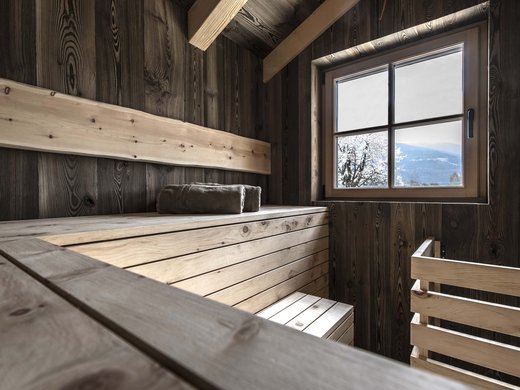 Chalet in Südtirol mit Sauna gesucht? Innenansicht einer Holzsauna mit Handtüchern und Fenster mit Bergblick