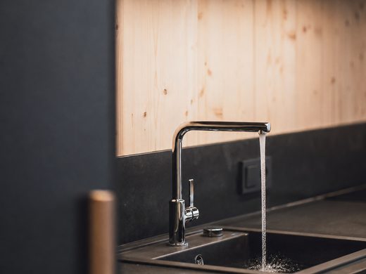 Fresh spring water - straight from the tap Kitchen faucet running water into a dark sink