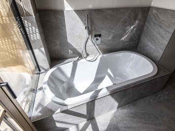 Chalet with a sauna and so much more: Kessler’s Modern bathtub with gray tiles and sunlight shadows