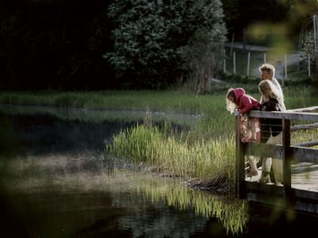 Holiday with a dog in South Tyrol: Kessler’s! Three people standing on a dock looking at the water of a lake