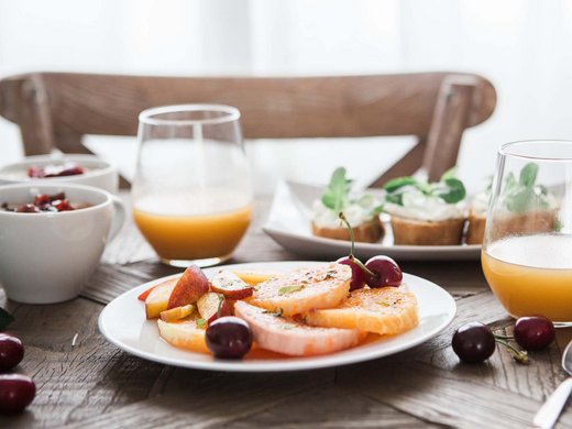 Luxuschalet in Südtirol: willkommen in Kessler’s! Frühstückstisch mit Obst, Orangensaft und Gebäck auf Holztisch